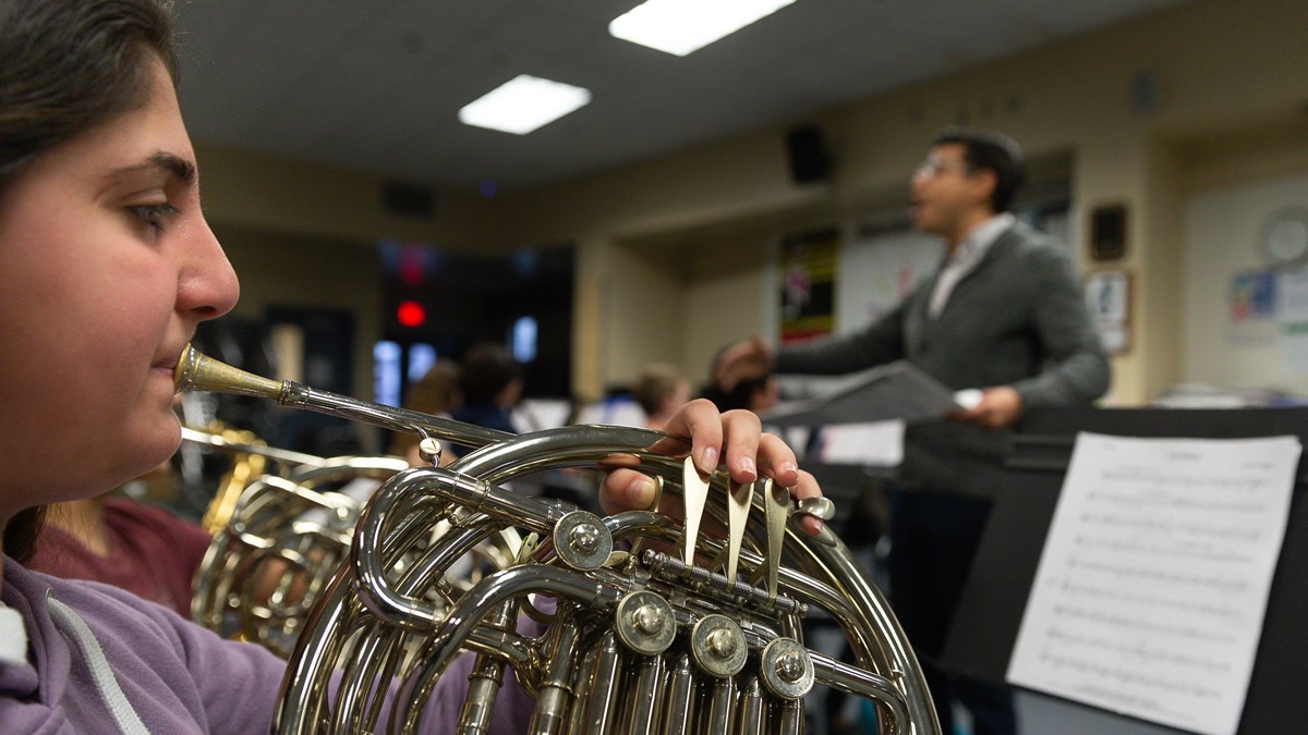 French horn player with director in background